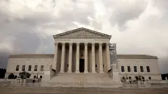 The front of US Supreme Court building with grey clouds above it.