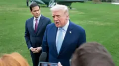 Perezida Donald Trump muri costime y'ubururu, ishati yera n'ikaruvato y'ubururu, ariko aboneka ko ariko arishura ahagaze umunyamakuru yashize micro imbere yiwe, i buryo bwiwe hari Marco Rubio, umushikiranganji wiwe ajejwe imigenderanire 