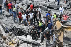 عناصر من الدفاع المدني اللبناني ومواطنون يجرون عمليات بحث بين أنقاض مبنى مدمّر في بلدة دير الزهراني، عقب غارة جوية إسرائيلية على جنوب لبنان.