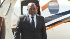 Joseph Kabila yambaye ikositimu y'umukara, karuvati y'umukara n'ishati y'umweru. Arimo gusohoka mu ndege. 