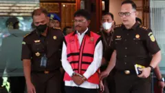 Menteri Komunikasi dan Informatika Johnny G Plate (tengah) berjalan menuju mobil tahanan usai menjalani pemeriksaan di Kejaksaan Agung (Kejagung) pada Rabu (17/5)