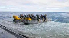 Os mergulhadores da Marinha dos EUA se preparam para embarcar em pequenas embarcações a partir do convés do USS John P. Murtha para resgatar os tripulantes da Artemis II