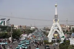 نمای از شهر هرات که در آن مردم و تردد موترهای تاکسی آبی رنگ دیده میشوند.