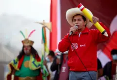 Pedro Castillo, con una chaqueta roja que dice "Perú" y un gran lápiz les habla a sus seguidores en un mitin en 2021.