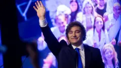 Javier Milei saluda a sus seguidores en un evento en la noche. 