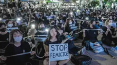At a protest in Seoul in 2022 a woman holds a sign saying 'stop femicide'