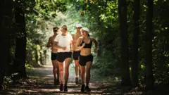 Grupo de quatro pessoas correndo em área verde