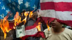 Иранцы жгут флаг и доллары США на демонстрации в Тегеране