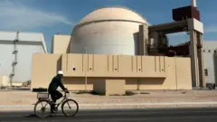 Seorang pekerja mengendarai sepeda di depan gedung reaktor pembangkit listrik tenaga nuklir Bushehr, pada Oktober 2010.