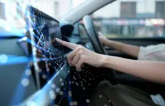 Uma mulher dirige enquanto interage com a tela multimídia do carro