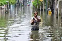 A man wades through a flooded road after heavy rainfall in Wellampitiya on the outskirts of Colombo on November 29, 2025. S