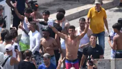 Migrantes atravessam a fronteira; alguns comemoram a chegada ao território espanhol.