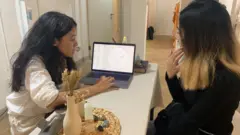 Çanti Widyadhari (kiri) membaca ramalan astrologi untuk Nana, seorang pelanggan