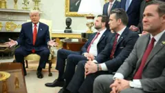 Donald Trump, JD Vance, Pete Hegseth e Mike Waltz sentados durante encontro em salão; Trump gesticula enquanto fala