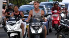 Turis asing mengendarai sepeda motor sewaan tanpa menggunakan helm di Jalan Pantai Kuta, Badung, Bali, Senin (13/3/2023).