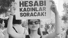 Esra Tokyaz siyah beyaz fotoğrafından Hesabı kadınlar soracak yazılı bir pankat tutuyor. 