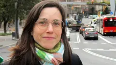 Maria Foraster, de óculos, em uma rua movimentada