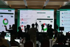 Varios reporteros y cámaras frente a las pantallas con el conteo de votos