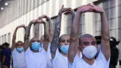 Detentos em Cecot com os braços levantados