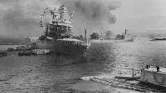 Navios com colunas de fumaça saindo deles após o ataque japonês a Pearl Harbor