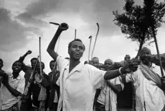 Homens em roupas civis, como camisas de manga curta, bradando armas rudimentares, como facas e bastões