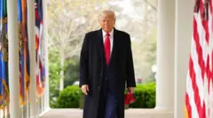 Donald Trump walking down a colonnade in the White House, flanked by flags on either side