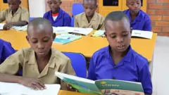 Abanyeshuri bari mu ishuri mu Rwanda, barimo gusoma, umwe biboneka ko afite igitabo cy'Icyongereza