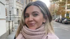 Mujer con una bufanda rosa camina por las calles de Londres