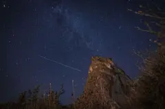 Kayan bir yıldız lacıvert ve karanlık gökyüzünde fotoğraflanmış. 