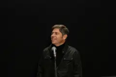 Axel Kicillof sonríe frente a un micrófono.