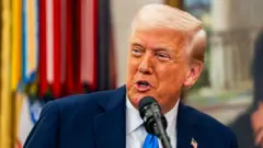 Trump on blue tie speaking to a mic