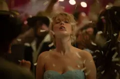 Jennifer Lawrence con los hombros descubiertos y una delicada gargantilla lleva la cabeza hacia atrás con sus ojos cerrados mientras le caen papelitos en lo que parece ser una fiesta formal.