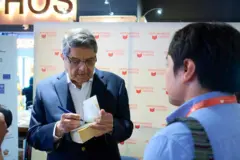 Una foto del escritor Sergio Ramírez autografiando un libro. Frente a él está un hombre que se ve de espaldas a la cámara.