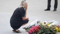 बोंडी बीच हमले में जान गंवाने वालों को श्रद्धांजलि देती एक महिला