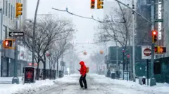 muškarac u crvenoj jakni s rancem na leđima prelazi ulicu