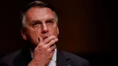 Jair Bolsonaro, um homem branco e idoso,  contra um fundo preto