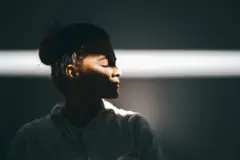 Mulher de perfil, com feixe de luz batendo na altura dos olhos