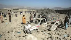 22 فروری 2026 کے پاکستانی حملے کے بعد افغان شہری ایک تباہ شدہ گاڑی کے پاس کھڑے ہیں