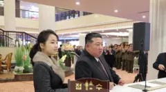 Młoda Koreanka z Północy i mężczyzna w średnim wieku stoją przy recepcji hotelowej.