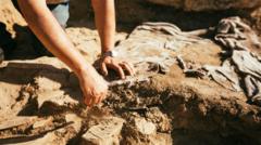 Mão de arqueólogo durante escavação em sítio arqueológico