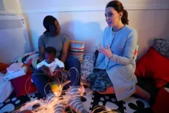 Mãe sentada no chão com seu bebê, em uma sala sensorial na unidade de mães e bebês