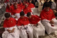 Membros de uma confraria católica maltesa, incluindo crianças que estão olhando para seus smartphones, participam do evento de boas-vindas na Basílica de São João de Latrão durante o Jubileu das Confrarias em 16 de maio de 2025 em Roma, Itália.