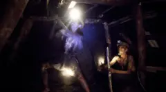 دو کارگر معدن در حال استخراج زغال سنگ از معدنی در سمنگان