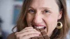 Uma mulher comendo uma barra de chocolate