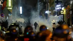 Rioters run as French police officers use tear gas in Paris on 2 July