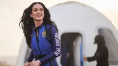 Katy Perry caminhando após viagem ao espaço da Blue Origin. Ela usa um macacão azul