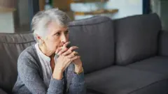 Mulher refletindo sentada em uma poltrona