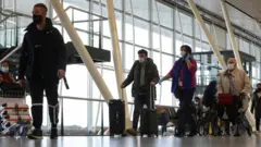 Abantu bagenda n'amaguru imbere mu kibuga cy'indege cya Schiphol Airport mu Buholandi