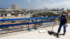 A woman looks at the damage caused by the explosion in Beirut