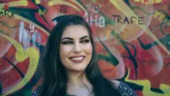 Nasmejana Ana Ilić ispred šarenog zida 